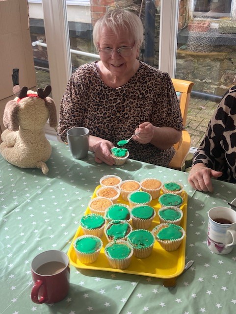Resident putting green icing on a cupcake 3