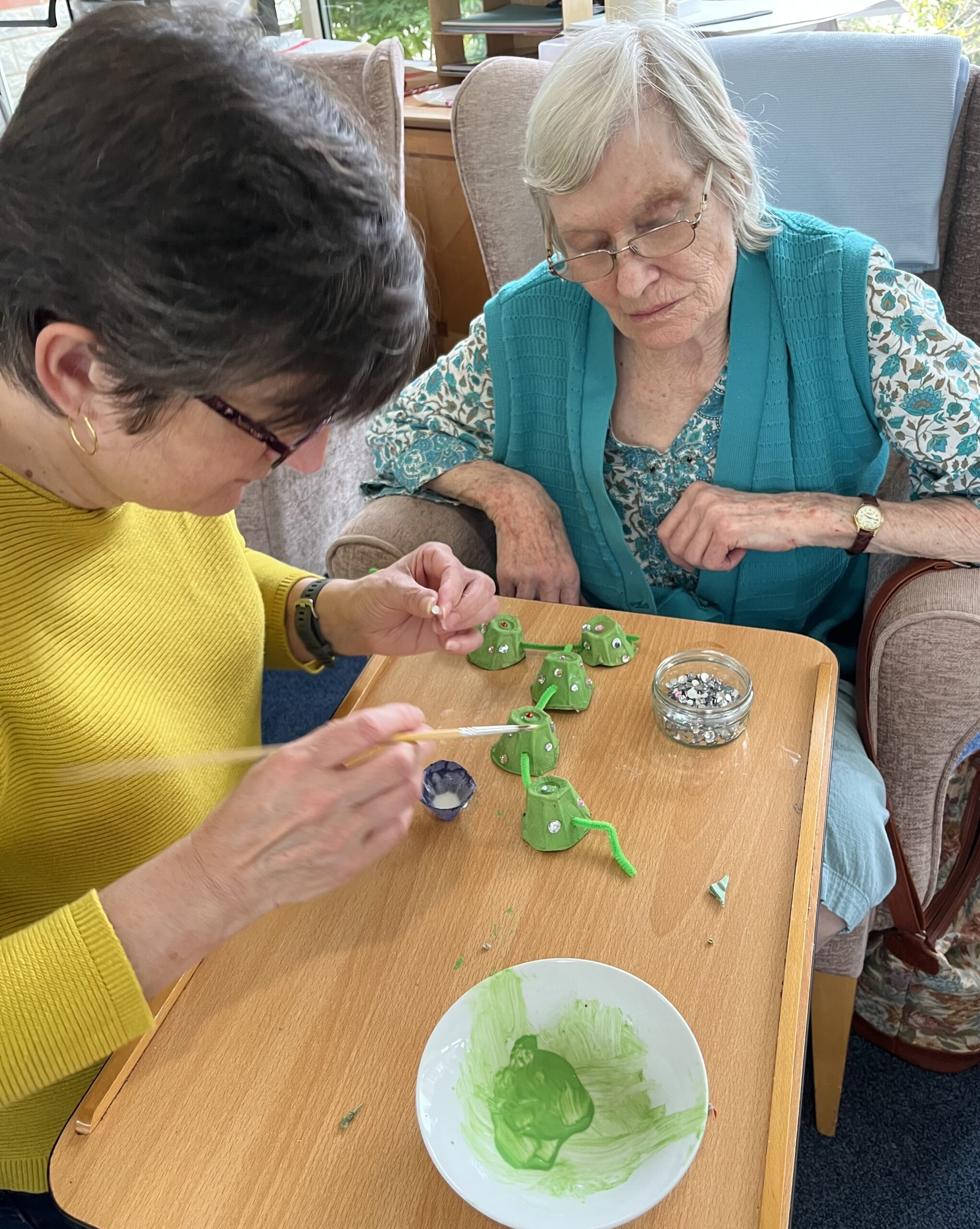 Wendy and helper gluing sequins to her dragon scaled
