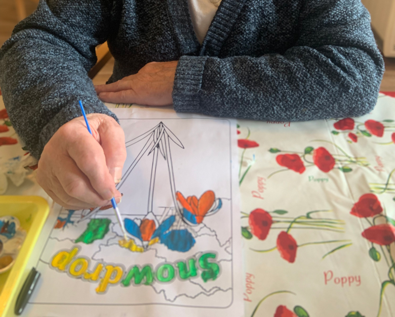 Another resident painting a colouring sheet of Snowdrops in bright colours