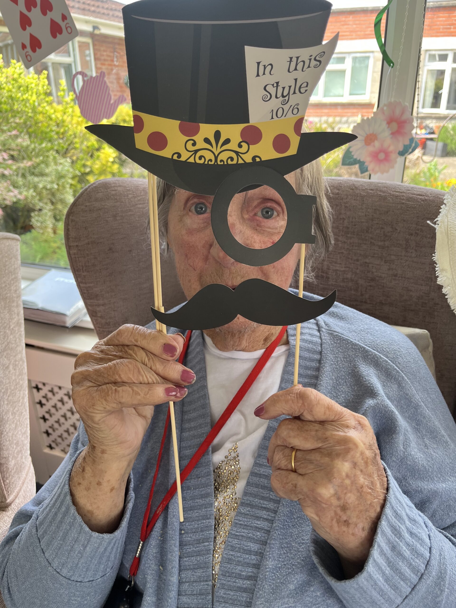 Barb holding paper cut outs of a top het eye monocle and moustache  scaled