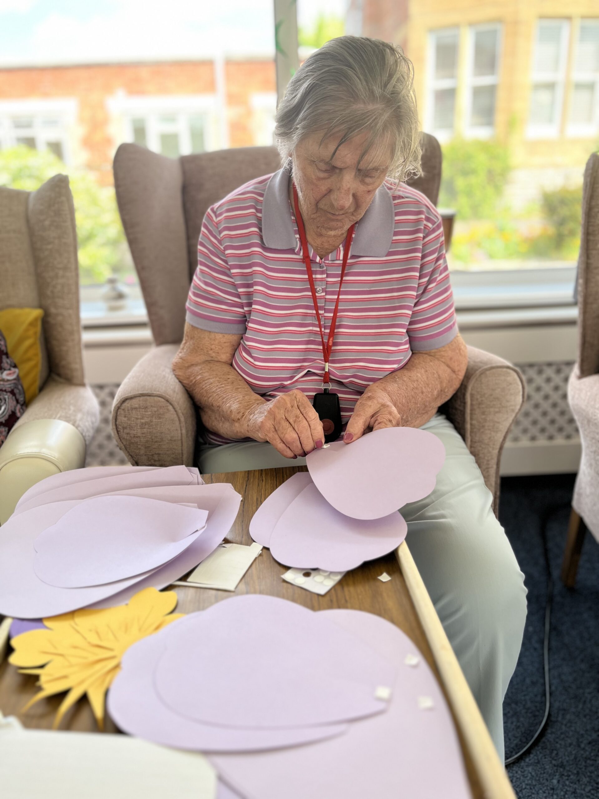 Barb putting sticky squares on her lilac paper flower petals scaled