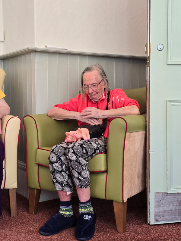 Barbara seated comfortably with the plastic pigs on her lap