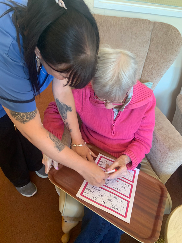 Carer helping female resident with her bingo sheet