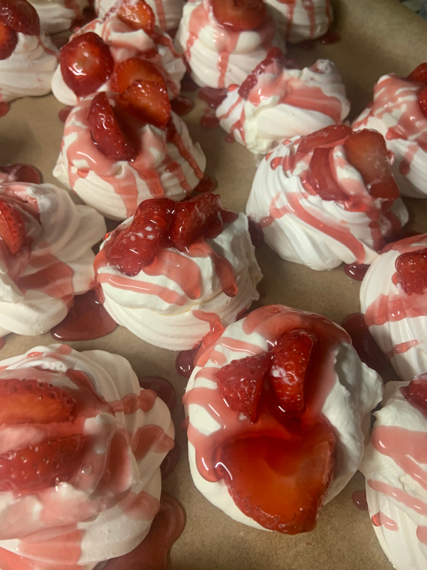 Closeup of finished pavlovas drizzled with strawberry sauce
