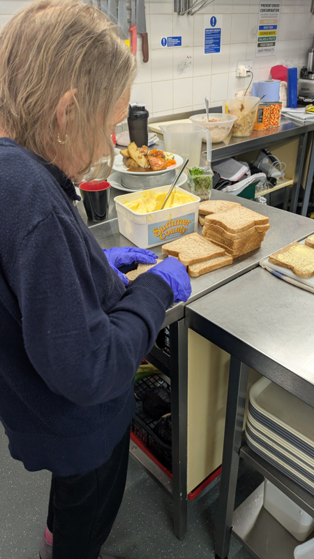 Female resident buttering pieces of bread for sandwiches