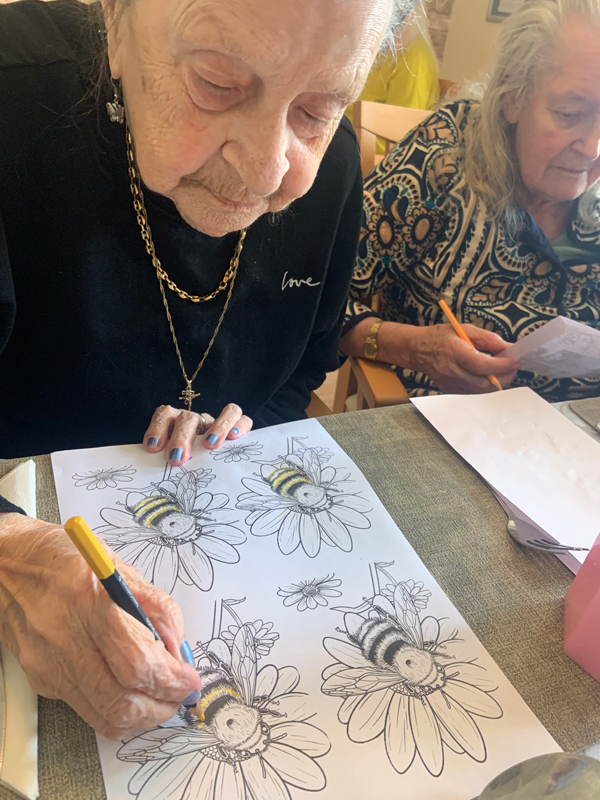 Female resident colouring in a bee with a yellow felt tip pen