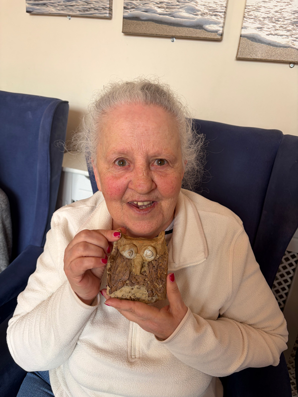 Female resident holding up her finished owl smiling