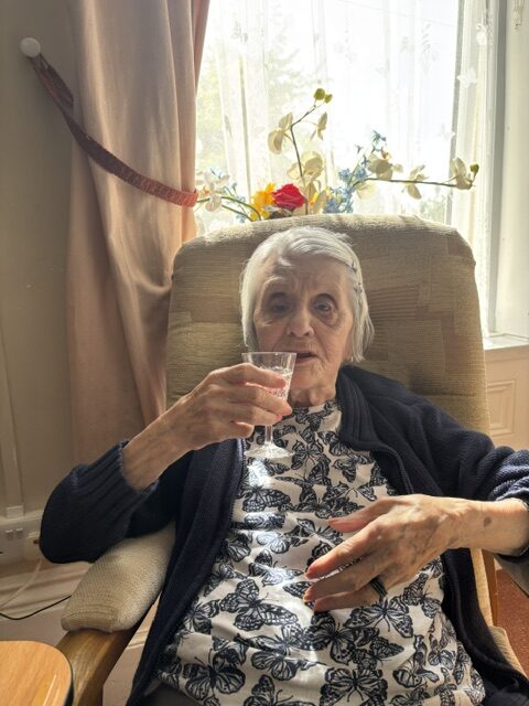 Female resident seated enjoying a glass of bubbly rotated