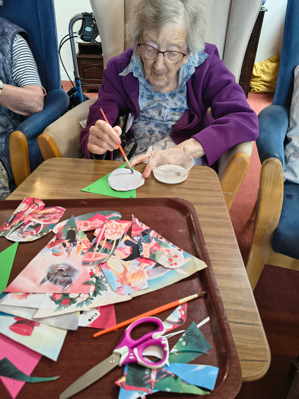 Female resident using a brush to put glue onto paper