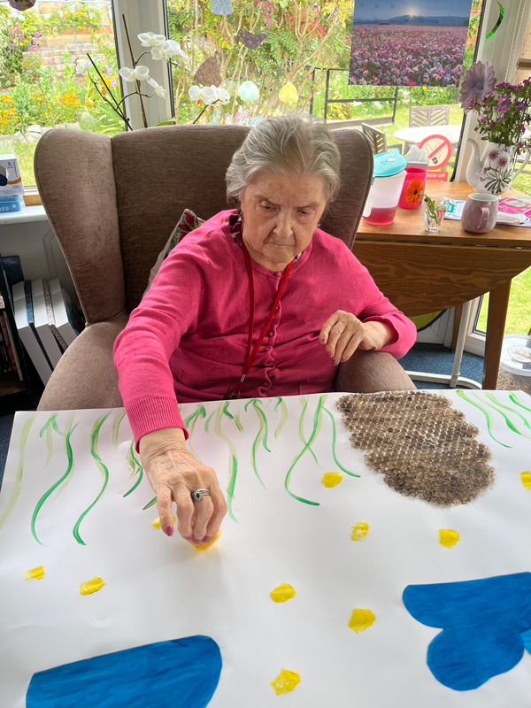 Herta adding yellow paint with a sponge to the poster for bees