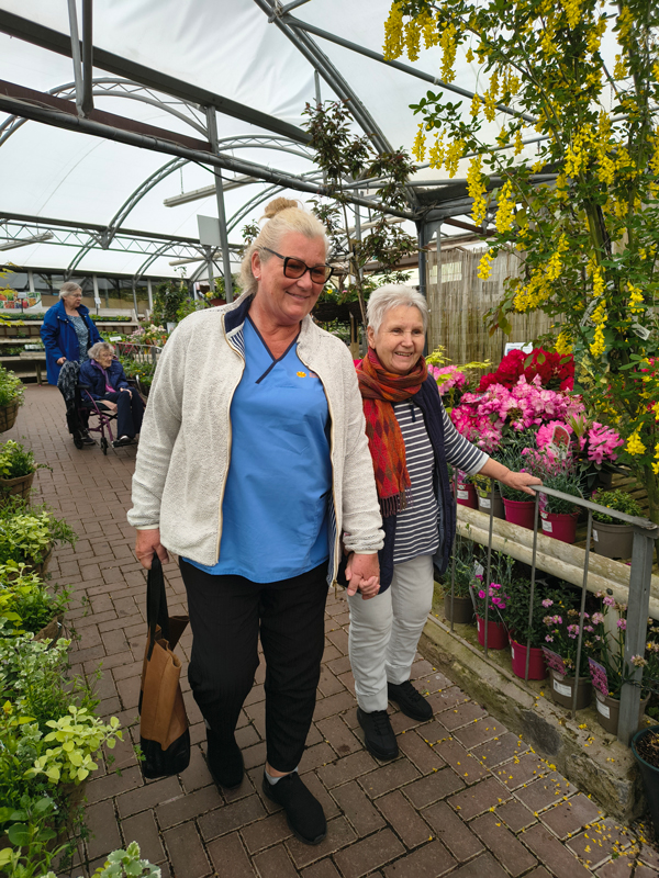 Resident and carer hand in hand walking at the garden centre