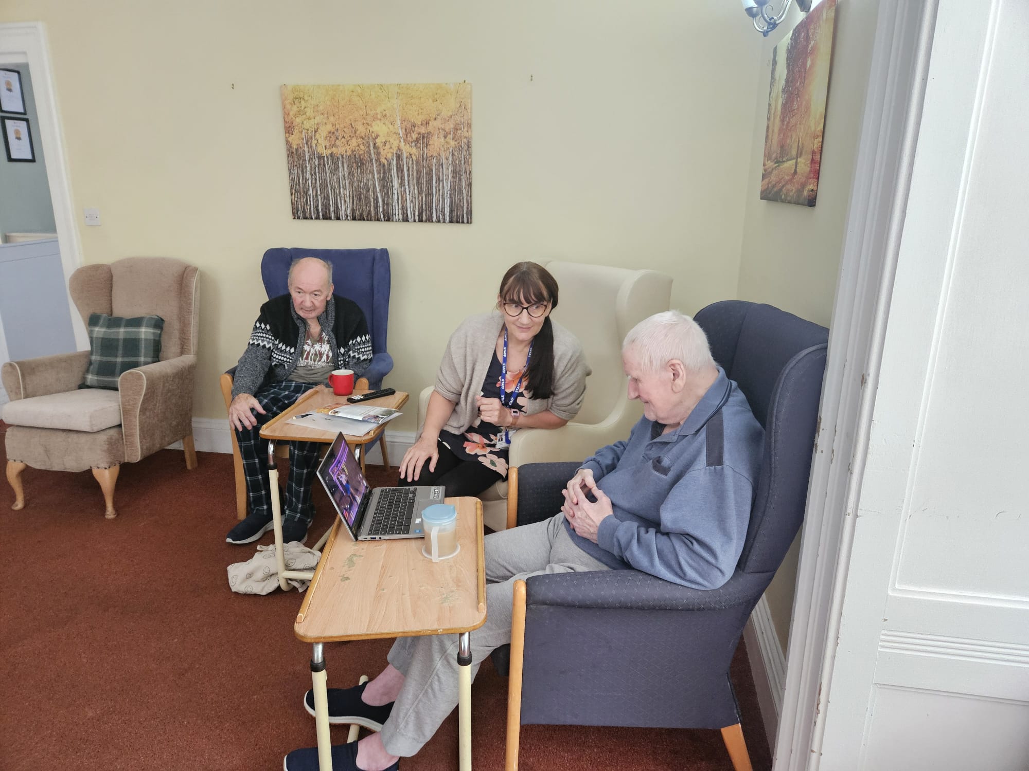 Residents and a staff member seated around a laptop watching a video and talking about it
