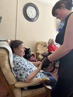Seated female resident having her hand massaged rotated