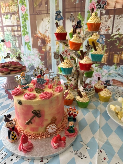 Table laid out with cakes cupcakes and Mad Hatter decorations 1
