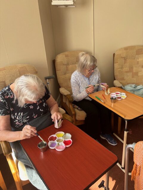 Two female residents seated side by side painting rotated