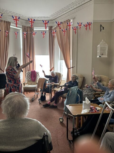 Zara singing to seated residents waving their flags rotated